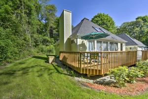 una casa verde con terraza con sombrilla en Charming East Falmouth House 4 Miles to Beach!, en East Falmouth