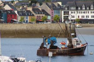 an old boat sitting in the water near a city at L'Imprenable vue mer in Crozon