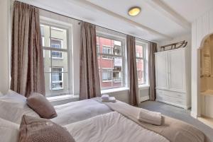 1 dormitorio con 1 cama grande y 2 ventanas en Jordaan Apartment 6, en Ámsterdam