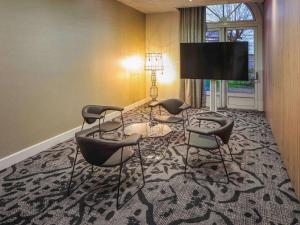 アングレームにあるメルキュール アングレーム オテル ド フランスの椅子4脚、薄型テレビが備わる客室です。