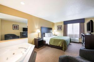 a hotel room with a bed and a bath tub at Quality Inn & Suites Menomonie in Menomonie