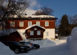 a house covered in snow with cars parked in front at Horské středisko Eljon in Špindlerův Mlýn
