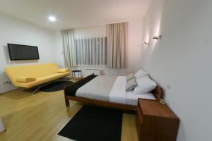 ein Schlafzimmer mit einem Bett und einem gelben Sofa in der Unterkunft Apartments & Rooms Krizevci in Križevci