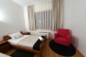 a bedroom with a bed and a red chair at Apartments & Rooms Krizevci in Križevci