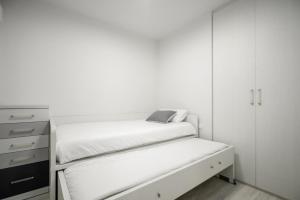 a white bedroom with a bed and a dresser at Picasso - Local Rentss in San Sebastián