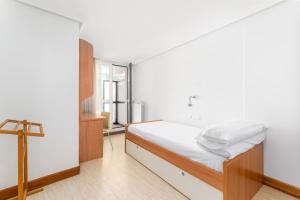 Un dormitorio con una cama con sábanas blancas y una cruz en Balea 8 - Local Rentss, en Orio