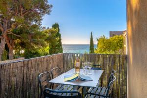 een tafel en stoelen op een balkon met uitzicht op de oceaan bij La Résidence du Bailli in Rayol-Canadel-sur-Mer