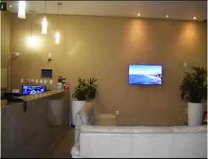 sala de estar con sofá y TV en la pared en Bahia Flat, en Salvador