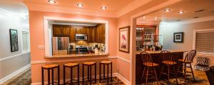 a kitchen with a bar with stools in it at Waterfront Villa with Deck - 23 Mi to French Quarter! in Venetian Isles