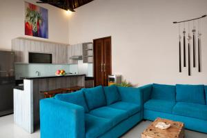 un soggiorno con divano blu e una cucina di Villa Apanya Sanur a Sanur