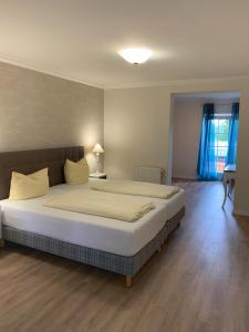 a bedroom with a large white bed with blue curtains at Landhotel Franck Garni in Brietlingen