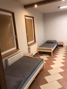 two beds in a room with a tiled floor at Apartament dla 4 osób in Dęblin