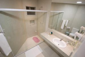 a bathroom with a shower and a sink and a mirror at Hotel Praia Dourada in Maragogi