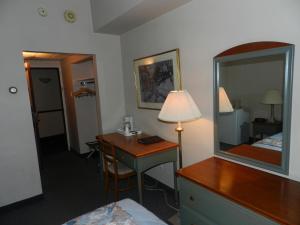 a hotel room with a desk and a mirror at L'Auberge de l'Aeroport Inn in Dorval