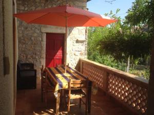 une table avec un parasol rouge sur une terrasse dans l'établissement mas cevenol, à Rosières