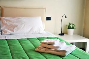 Una cama con sábanas verdes y toallas. en Villa Stefania, en Noventa Padovana