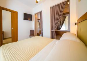- une chambre avec un lit blanc et une fenêtre dans l'établissement Mediterraneo Hotel & Suites, à Cattolica