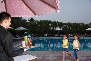 新德里的住宿－新德里泰姬陵酒店，一个人在游泳池前和两个孩子说话