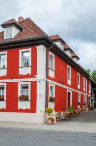 un edificio rojo y blanco con flores en las ventanas en Hotel Schuberths am Markt en Buttenheim