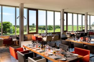 un ristorante con tavoli e sedie e grandi finestre di Parador de El Saler a El Saler
