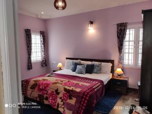 a bedroom with a bed with pink walls and windows at Adhithya Holidays in Kodaikānāl