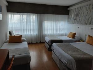 a hotel room with two beds and a window at Hotel Almirante in A Coruña