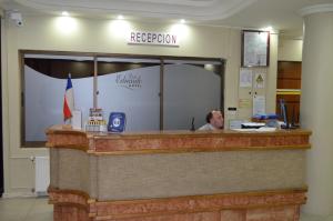 a man sitting at a reception desk in a room at Hotel Don Eduardo in Temuco