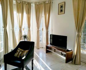 un salon avec une télévision, une chaise et une table dans l'établissement Le Palladium quartier Tzaréwitch Nice, à Nice