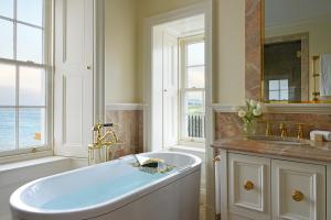 a white bathroom with a tub and a sink at Trump Turnberry in Turnberry