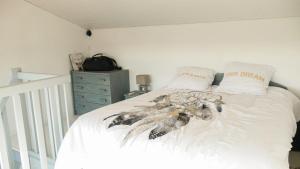 a bedroom with a bed with white sheets and a dresser at Appartement Cosy Seignosse bord de mer in Seignosse