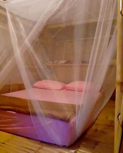 a bed covered in mosquito nets on a wooden floor at Bamboo Bungalow Baan Tai Phangan in Baan Tai
