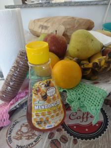 a bowl of fruit with a bottle of marmitemite sauce at Um quarto em casa agradável in Perequê