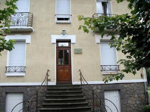 a building with a door and stairs in front at Doux Ombrages in La Bourboule