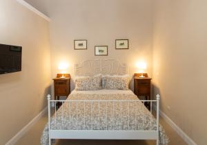sypialnia z białym łóżkiem i 2 szafkami nocnymi w obiekcie Dimora Porta Garibaldi w Katanii