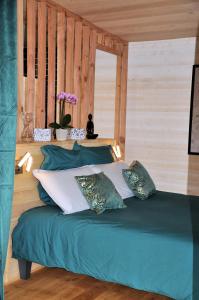 - un lit avec des draps et des oreillers verts dans l'établissement La Parenthèse, à Bergerac