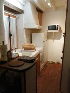 małą kuchnię z białą lodówką i stołem w obiekcie La maison de Xenos w mieście Nohant-en-Graçay