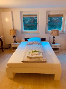 a white bed in a room with two windows at Souterrain Zimmer mit separatem Eingang und Bad in Düsseldorf