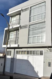 una casa blanca con dos puertas blancas de garaje en MUNAY TTIKA Hoteles, en Moquegua