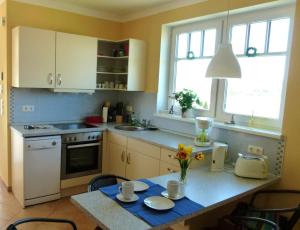 a kitchen with white cabinets and a table with flowers on it at "Strand-Gut" in Börgerende-Rethwisch