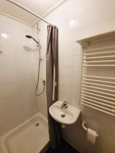 ein weißes Bad mit einem Waschbecken und einer Dusche in der Unterkunft Tuinhuis in Schagen