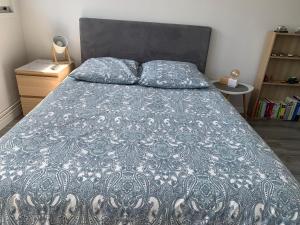 a bed with a blue comforter and two pillows at Suite au Parc de Fresnoy in Roye