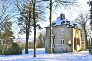 una gran casa de piedra en la nieve con árboles en Le Soyeureux Holiday Cottage Villa Spa, en Spa