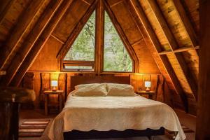 ein Schlafzimmer mit einem Bett und einem großen Fenster in der Unterkunft Cabañas Ecoturismo la Pancha in Puerto Aisén