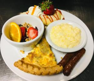 a plate of breakfast food with eggs sausage and fruit at Lake Rabun Hotel in Lakemont