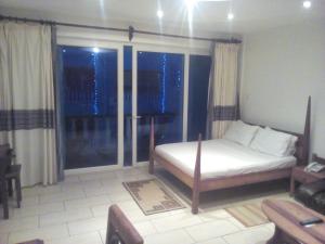 a bedroom with a bed and a large window at Cowrie Luxury Beach Studio in Mombasa