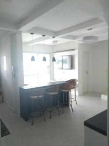 cocina con mesa y taburetes en una habitación en Duplex lindo sofisticado, en Governador Celso Ramos