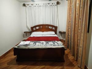 a bedroom with a bed with a wooden headboard and curtains at Green Hostal Popayan in Popayan