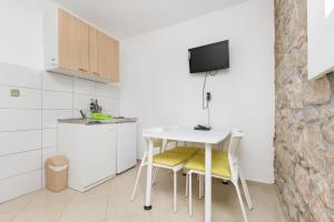 una pequeña cocina con mesa blanca y sillas en Rooms Pama, en Split