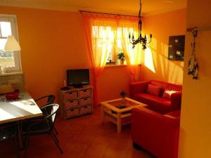 a living room with a red couch and a table at "Strand-Gut" in Börgerende-Rethwisch