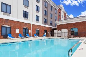 een zwembad met stoelen en een gebouw bij Holiday Inn Express Hotel & Suites Montgomery Boyd-Cooper Parkway, an IHG Hotel in Montgomery